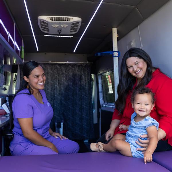 WIC clinic staff and participants are smiling at each other during a visit at the Chickasaw Nation WIC Mobile Van.